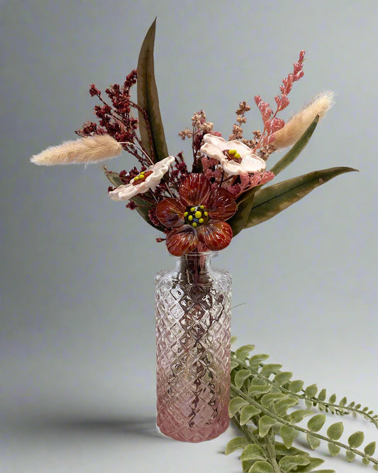 Decorative floral arrangement in a textured pink vase on a light background