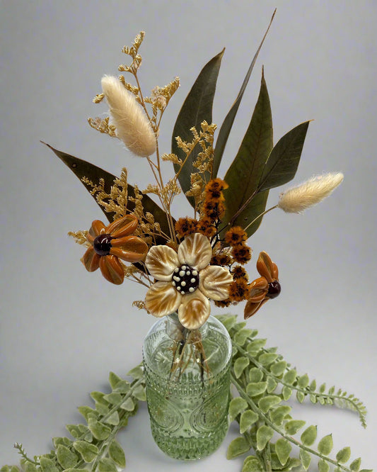 Decorative flower arrangement in a glass bottle on a light background