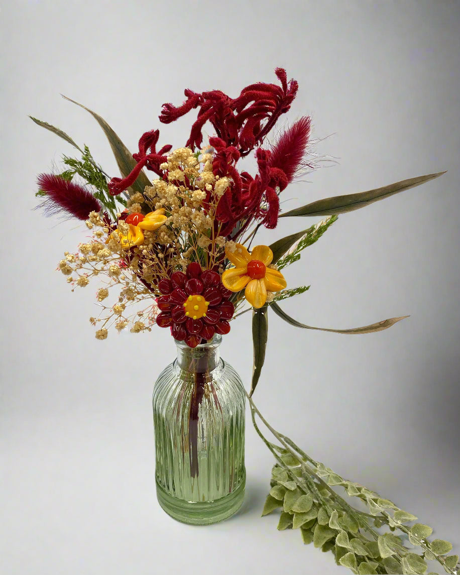 Bouquet of flowers in a green glass bottle on a white background