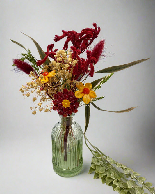 Bouquet of flowers in a green glass bottle on a white background