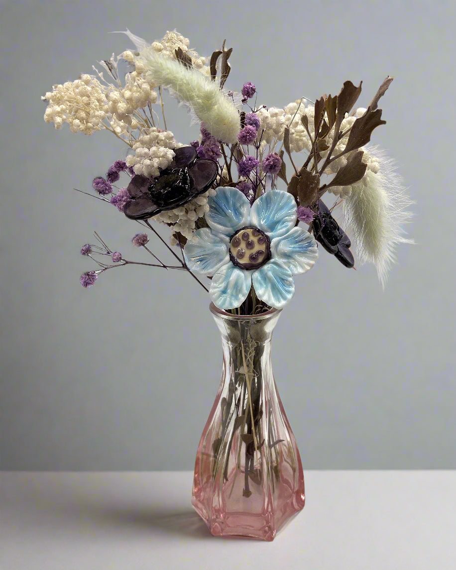 Pink glass vase with dried flowers on a white background