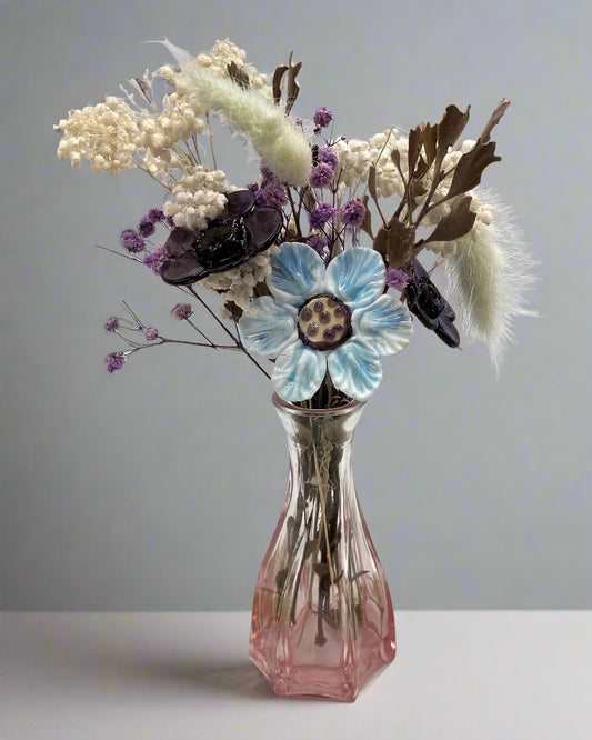 Pink glass vase with dried flowers on a white background